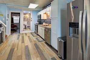 A modern kitchen with stainless steel appliances, a wooden floor, and a view into a bedroom. - Marcaritaville at La · Marcaritaville at Lake Barkley (Kuttawa)