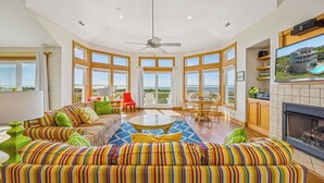 A spacious living room with a large sofa set, a dining table, and a fireplace. - Soundfront Dog Friendly Home w/ Pool, Hot Tub, Elevator, Private Sound Boardwalk (Avon)