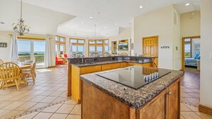 A spacious kitchen with a large island, wooden cabinets, and a view to the outside. - Soundfront Dog Friendly Home w/ Pool, Hot Tub, Elevator, Private Sound Boardwalk (Avon)