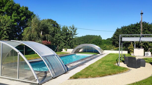 A swimming pool with a glass enclosure and a pergola structure.