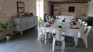 A dining area with a white table set for a meal, surrounded by white plastic chairs.
