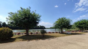 A gravel path leading to a lakeside area with trees and a wooden fence.