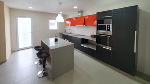 Una cocina moderna con una isla central, armarios negros y un microondas.
