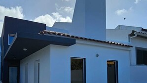 Una casa moderna con techo plano, una chimenea y dos ventanas.