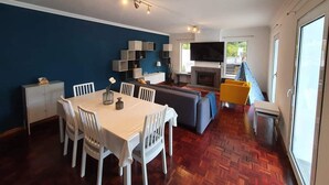 Una sala de estar moderna con comedor, chimenea y un ventanal grande.