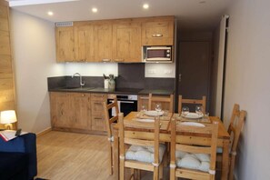 Une cuisine compacte avec des meubles en bois, un four à micro-ondes et une table à manger pour quatre personnes.