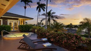 A pool area with lounge chairs and a hot tub, surrounded by palm trees and flowering bushes. - Pineapple House: Ocean View Home in Keauhou Estates w/ Private Hot Tub, BBQ & AC (Kailua Kona)