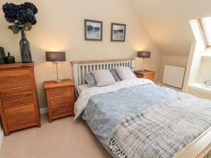 A bedroom with a bed, two bedside tables, a dresser, and a window with a view of a lake. - Calm Skies (Berwick-upon-Tweed)