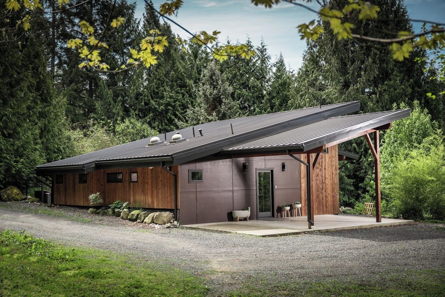 Een moderne cabin met een schuin dak, een overdekte veranda en een stenen fundering.
