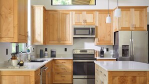 A modern kitchen with wooden cabinets, stainless steel appliances, and a large window providing natural light.