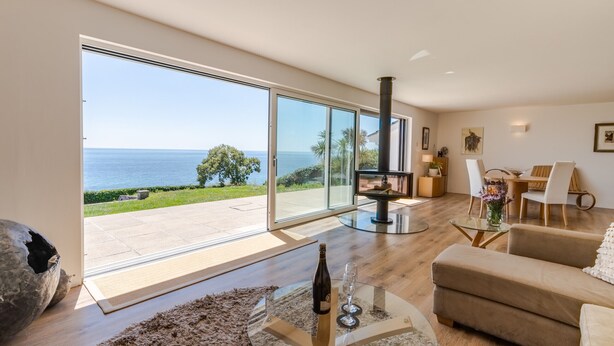 Un salon spacieux doté d’une grande porte vitrée donnant sur un balcon avec vue sur la mer.