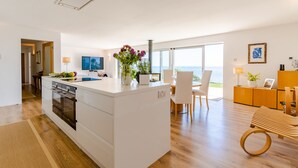 Une cuisine moderne dotée d’un îlot central, d’un coin repas offrant une vue agréable et d’un espace de vie agrémenté d’un banc en bois.