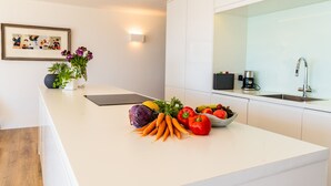 Une cuisine moderne avec des meubles blancs, un plan de travail blanc et une variété de légumes frais.