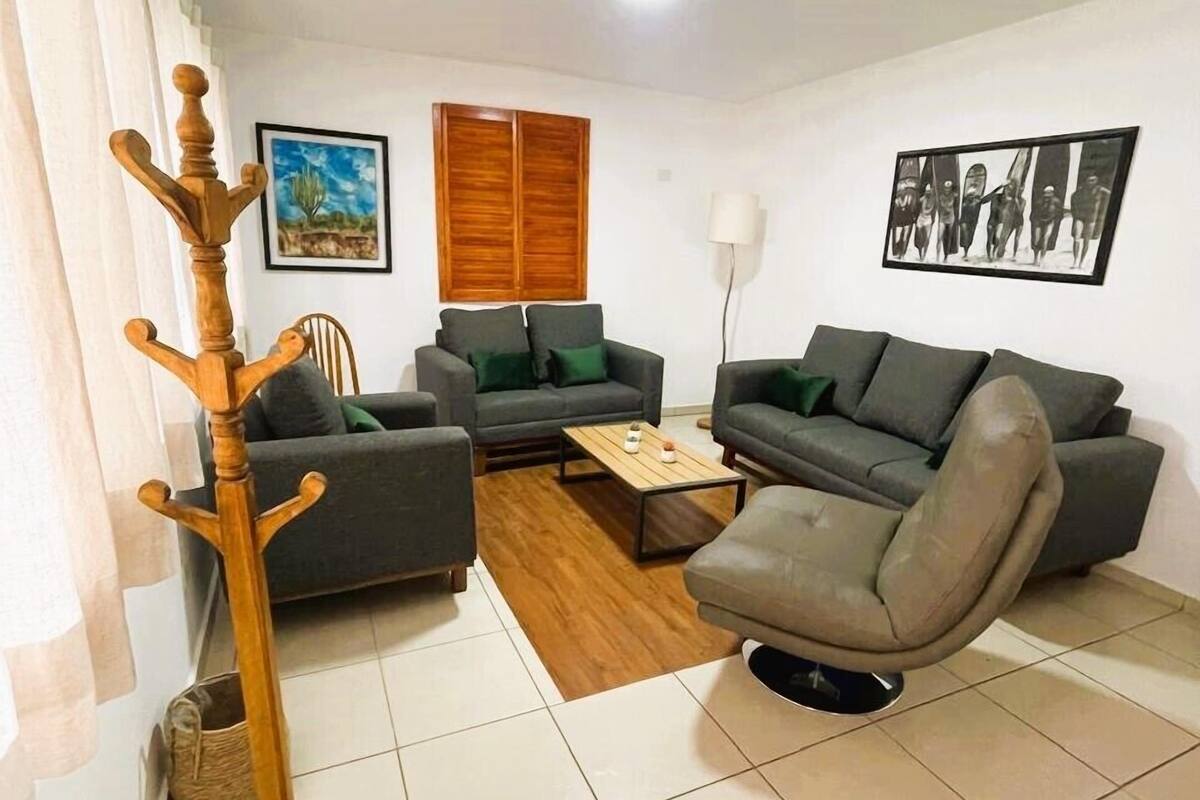 A living room with a sofa, armchair, wooden coat stand, and a coffee table.