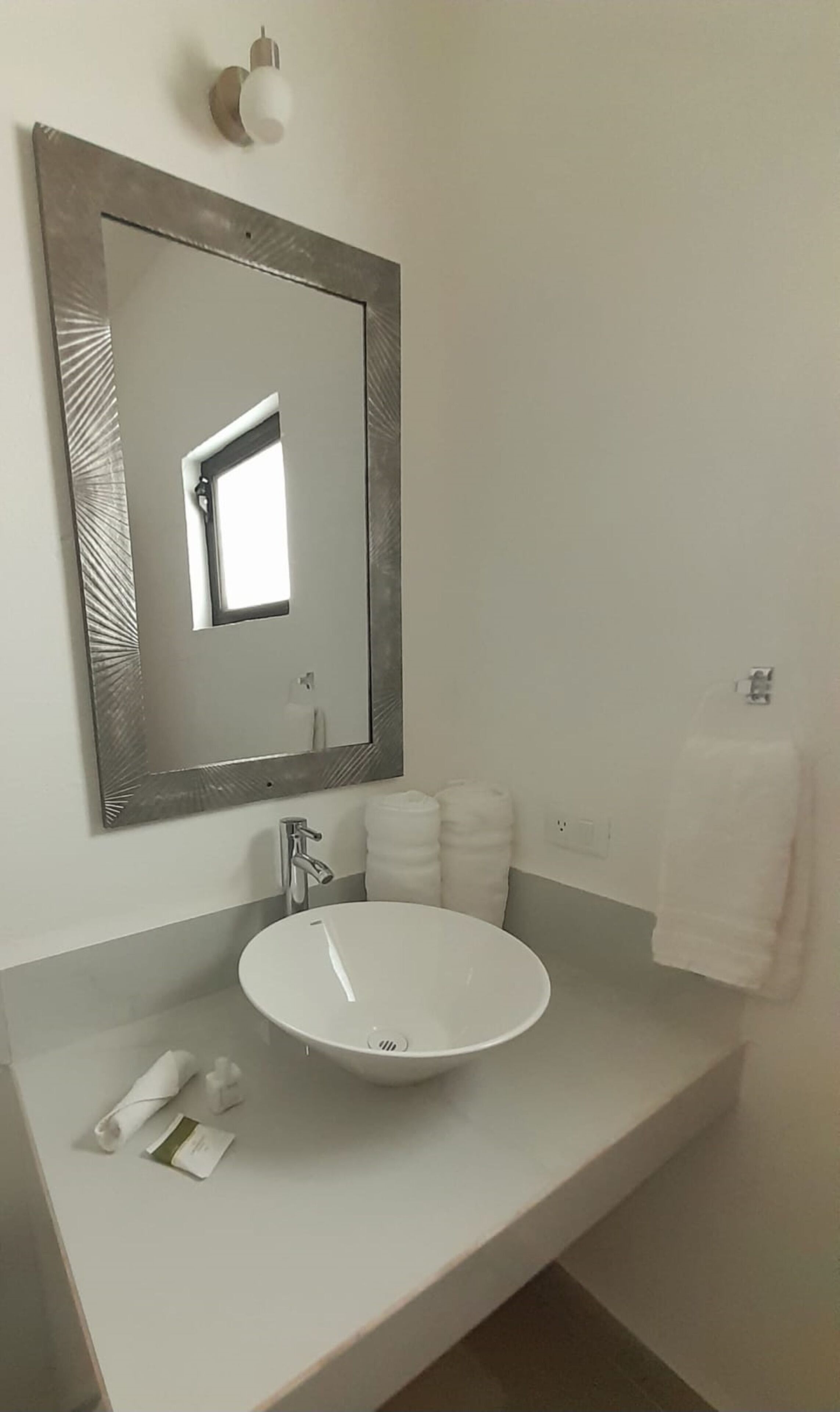 A bathroom with a white sink, a large mirror, and a towel rack.