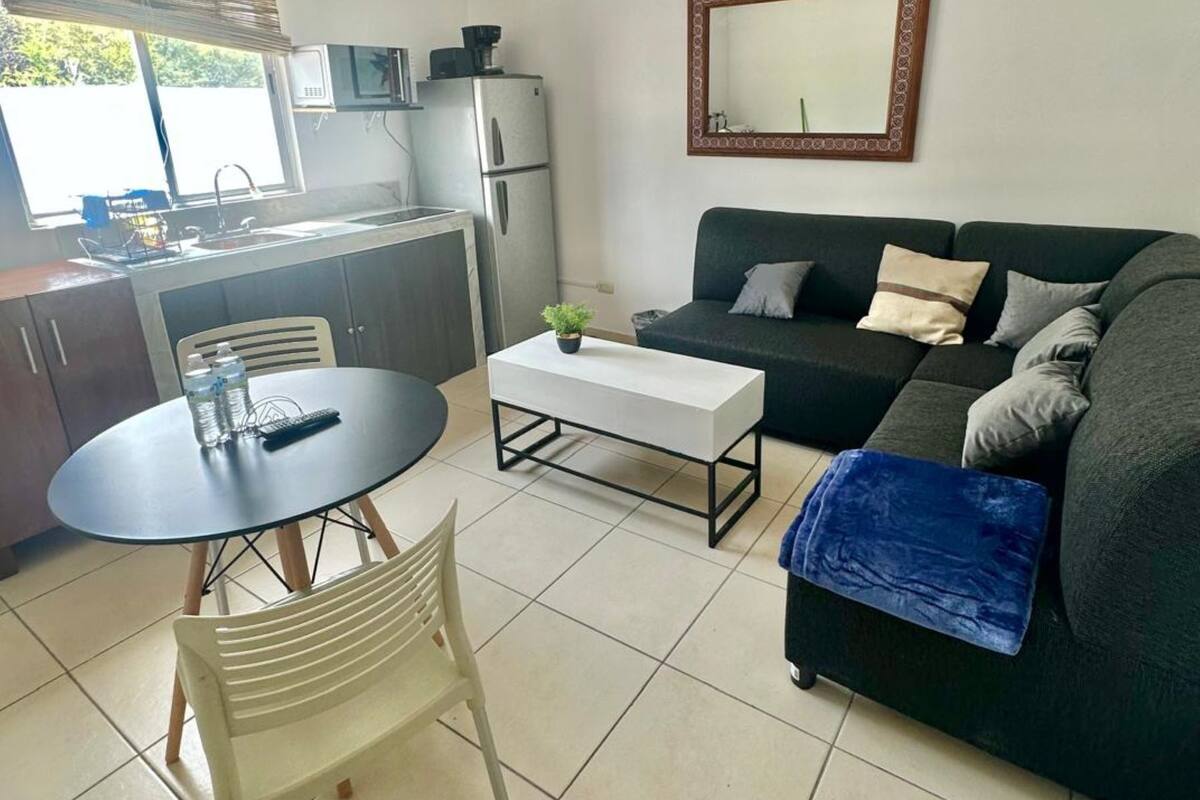 A compact living space with a kitchenette, a sofa, a coffee table, and a dining table.