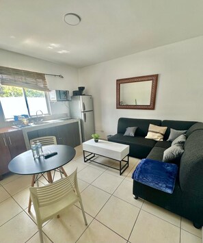 A compact living space with a kitchenette, a sofa, a coffee table, and a dining table.