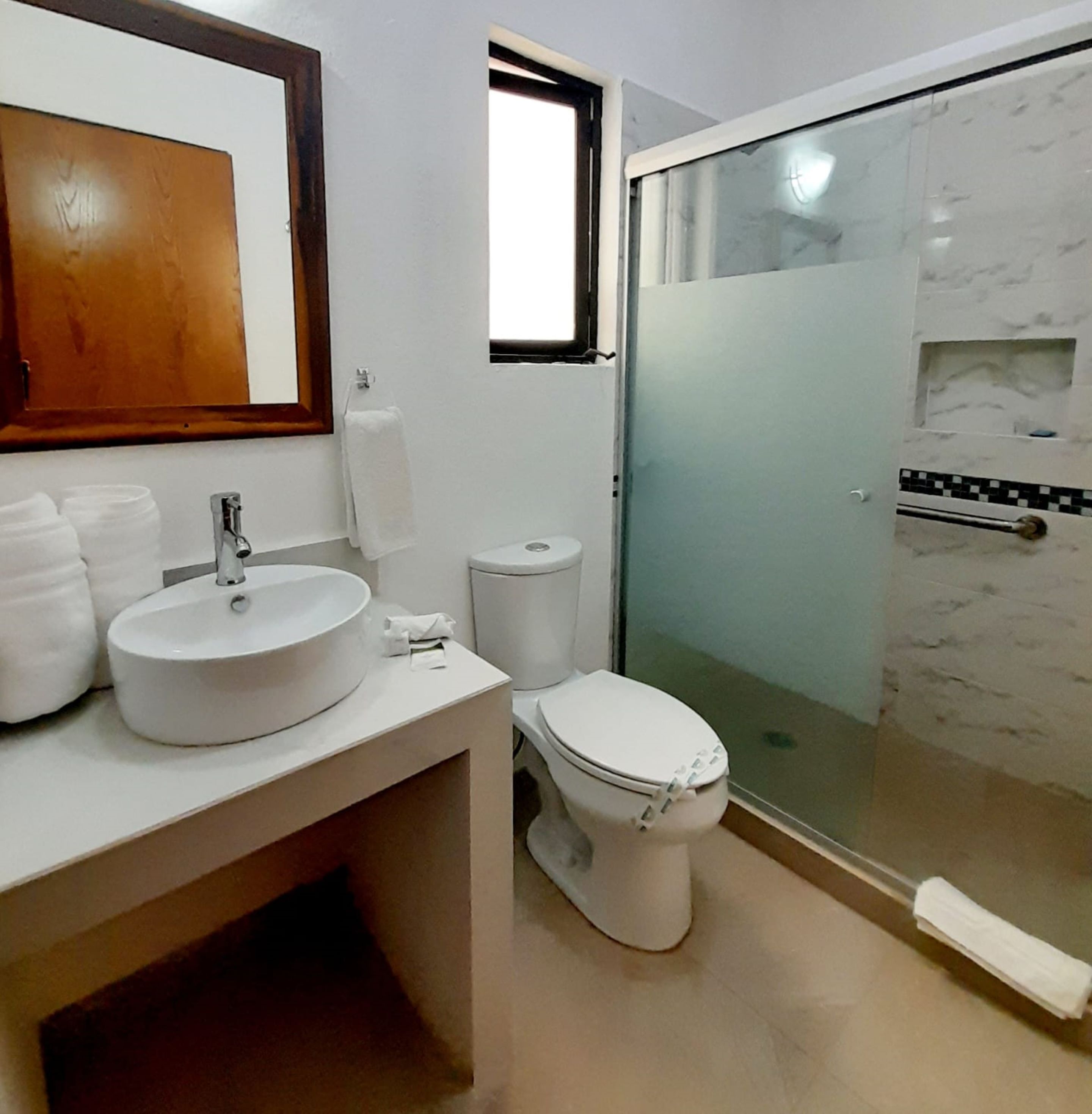 Ein Badezimmer mit rundem Waschbecken, Toilette und einer Duschkabine.