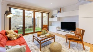 A modern living room with a sofa, armchair, coffee table, and TV. - Farrah - Designer, Three Bedroom Carlton Residence (Carlton)