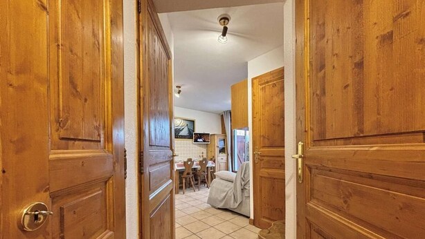 A hallway with wooden doors leading to a dining area with a table and chairs. - Ground floor, view mountain, terrace, tv, ski locker, 29m², Praz sur Arly (Praz-sur-Arly)