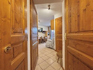 Un couloir avec des portes en bois qui donnent sur une salle à manger équipée d’une table et de chaises.