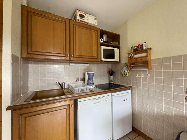 Une cuisine avec des meubles de rangement en bois, un four à micro-ondes, un lave-vaisselle et une machine à café.