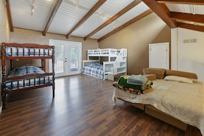 A bedroom with a wooden floor, a large bed, two bunk beds, and a desk.