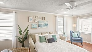 Un dormitorio con una cama grande, ventilador de techo y vistas al exterior a través de la ventana.