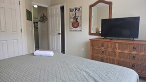 A bedroom with a bed, a dresser, a television, and a poster on the wall. - Big house with private pool near to Dinsey and other theme parks (Kissimmee)