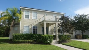 A two-story residential building with a covered front porch, a small front yard, and a tree to the right. - Big house with private pool near to Dinsey and other theme parks (Kissimmee)