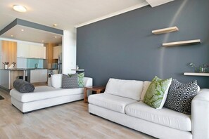 A modern living room with a white sofa, a coffee table, and a grey accent wall.