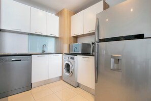 Eine moderne Küche mit Geschirrspüler, Waschmaschine, Mikrowelle und Kühlschrank.