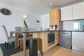 Een moderne keuken met een houten kookeiland, roestvrijstalen apparatuur en een eetgedeelte met een glazen tafel en stoelen.