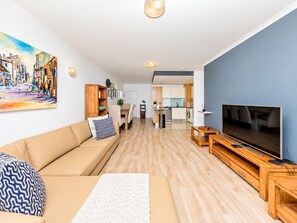 A modern living room with a sofa, a coffee table, a TV, and a painting on the wall.