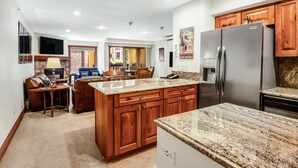 A spacious kitchen with granite countertops, wooden cabinets, and a stainless steel refrigerator. - Ski In and Out Condo in Lionshead Village w/ Pool, Hot Tubs, and Lovely Views (Vail)