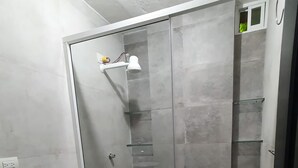 Un baño con inodoro, ducha con cerramiento de vidrio y lavamanos.