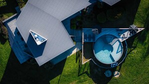 An aerial view of a modern house with a unique triangular roof design, a large circular water feature, and a well-maintained lawn. - 'the sticks' - Sleeps 10, 5 Ensuites, Pool, Fire (Upper Kangaroo River)