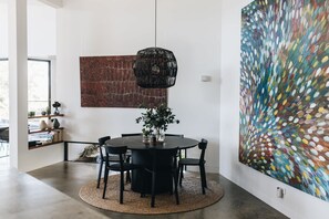 A modern dining area with a round table, black chairs, and a woven rug.