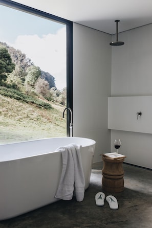 Une salle de bain moderne avec une baignoire sur pieds, un tabouret en bois et un verre à vin.