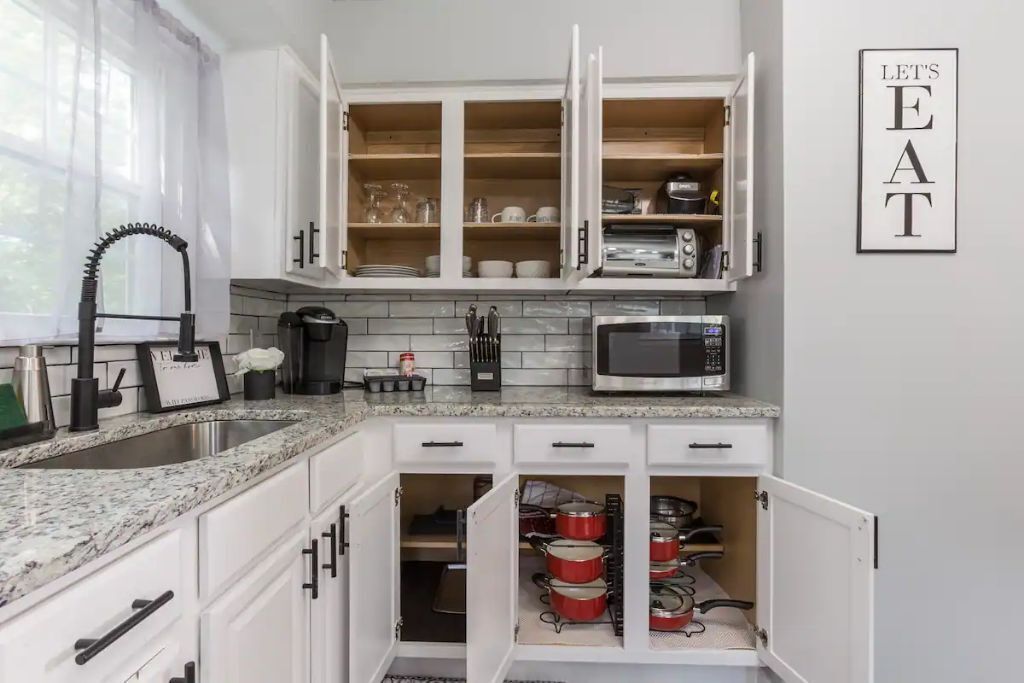 A kitchen with white cabinets, a granite countertop, a microwave, and a 'Let's Eat' sign.