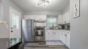 A modern kitchen with white cabinets, stainless steel appliances, and a black countertop.