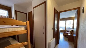 A room with bunk beds, a radiator, and a view of a balcony with a sofa. - 1st floor, balcony, parking, tv, ski locker, 29m², Praz sur Arly (Praz-sur-Arly)