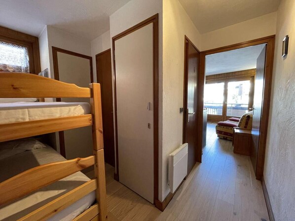 A room with bunk beds, a radiator, and a view of a balcony with a sofa.