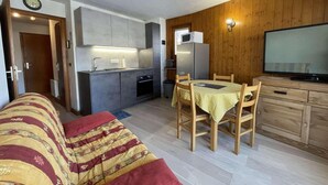 A compact living space with a kitchenette, a dining area, and a TV. - 1st floor, balcony, parking, tv, ski locker, 29m², Praz sur Arly (Praz-sur-Arly)