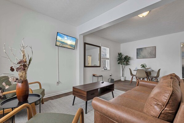 A modern living room with a leather sofa, a coffee table, and a TV mounted on the wall.