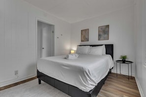 A neatly arranged bedroom with a bed, bedside table, and two wall-mounted paintings.