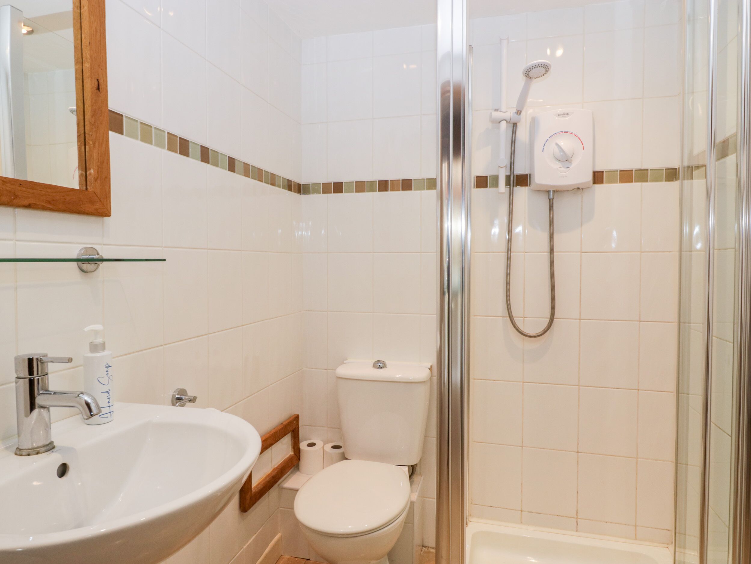 A bathroom with a glass shower enclosure, a white sink, and a toilet.