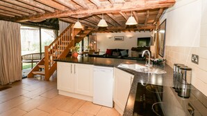 Een moderne keuken met een houten plafond, een ingebouwde vaatwasser en een groot kookeiland met spoelbak en fornuis.