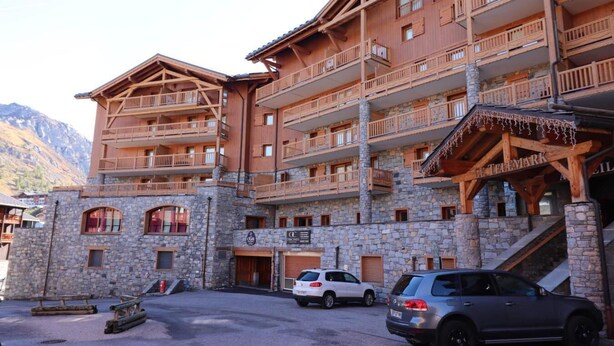 A multi-story wooden building with balconies, stone walls, and a sign reading "Hotel".