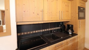 A kitchen with wooden cabinets, a black countertop, a coffee maker, and a built-in oven.